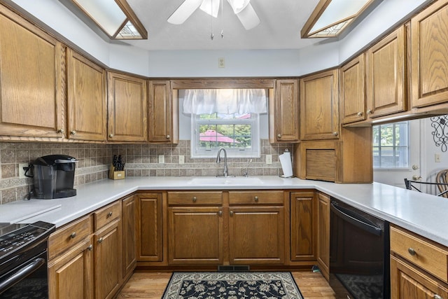 kitchen featuring black appliances, ceiling fan, light hardwood / wood-style floors, and sink