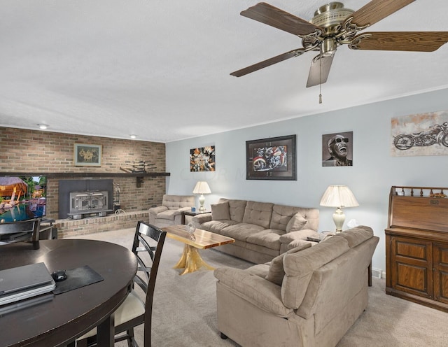 living room with ceiling fan, light colored carpet, a wood stove, and brick wall