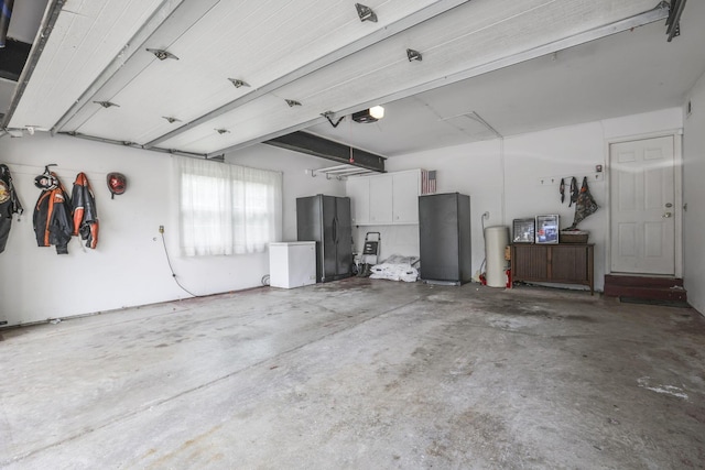 garage featuring black refrigerator, white fridge, and a garage door opener