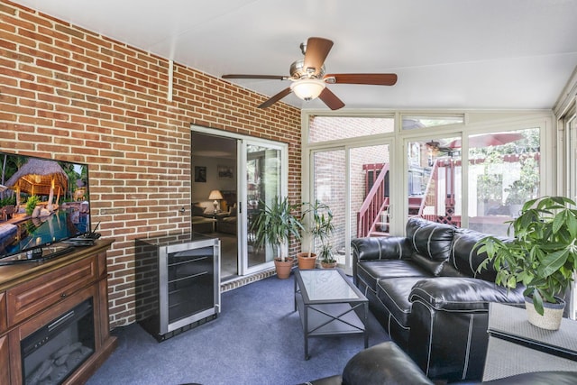 carpeted living room featuring ceiling fan, lofted ceiling, and brick wall