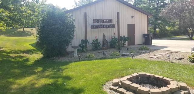 view of outbuilding featuring a fire pit and a yard