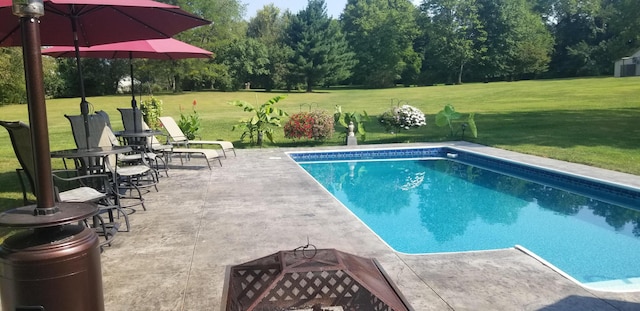 view of swimming pool featuring a fire pit, a yard, and a patio