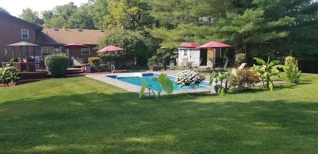 view of swimming pool featuring a lawn, a storage shed, and a wooden deck