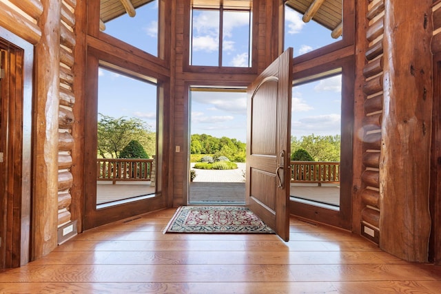 doorway to outside with beamed ceiling, high vaulted ceiling, and hardwood / wood-style flooring