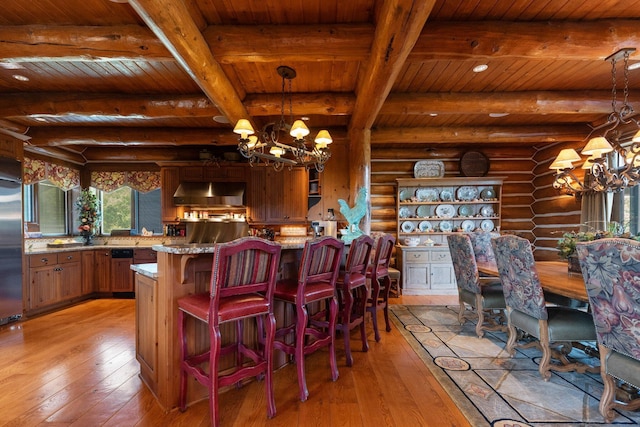 kitchen featuring wall chimney exhaust hood, wood ceiling, rustic walls, and light hardwood / wood-style flooring