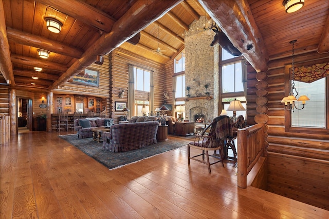 living room featuring a stone fireplace, beamed ceiling, high vaulted ceiling, wood ceiling, and hardwood / wood-style flooring