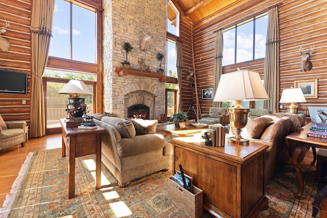 living room with light wood-type flooring, rustic walls, wood ceiling, high vaulted ceiling, and a fireplace