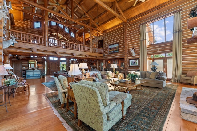 living room with high vaulted ceiling, wood-type flooring, log walls, beamed ceiling, and wood ceiling