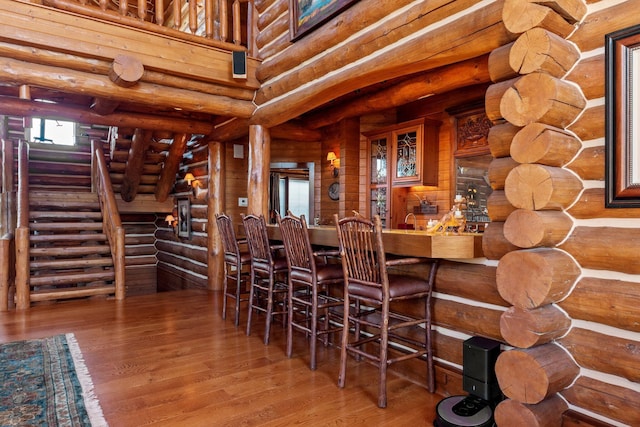 interior space with bar area, hardwood / wood-style flooring, and rustic walls