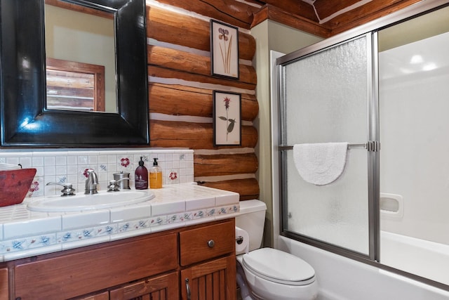 full bathroom with vanity, wood walls, decorative backsplash, toilet, and enclosed tub / shower combo