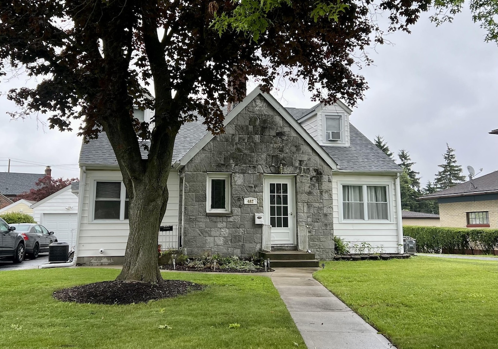 view of front of home with cooling unit and a front lawn