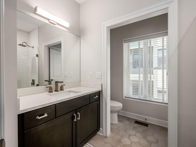 bathroom with tile patterned flooring, a tile shower, vanity, and toilet