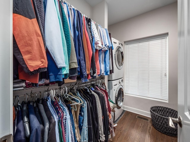 walk in closet with dark hardwood / wood-style flooring and stacked washing maching and dryer