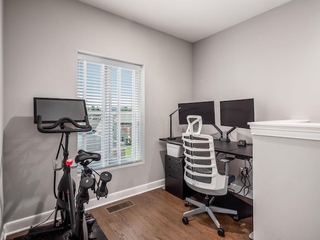 home office with dark hardwood / wood-style flooring and a healthy amount of sunlight