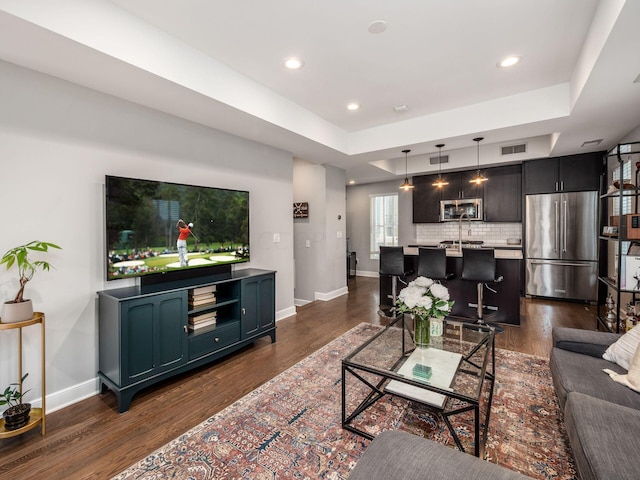 living room with dark hardwood / wood-style floors and a raised ceiling