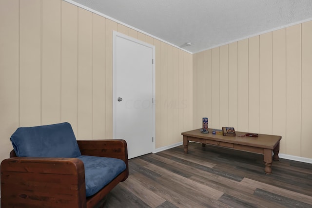 sitting room featuring crown molding, wood walls, dark hardwood / wood-style flooring, and a textured ceiling