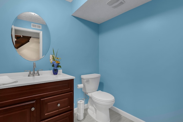 bathroom featuring vanity, toilet, and a textured ceiling