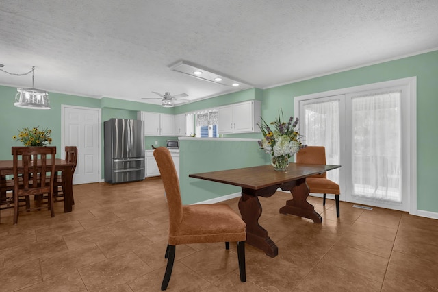 tiled dining room featuring ceiling fan, crown molding, and a textured ceiling