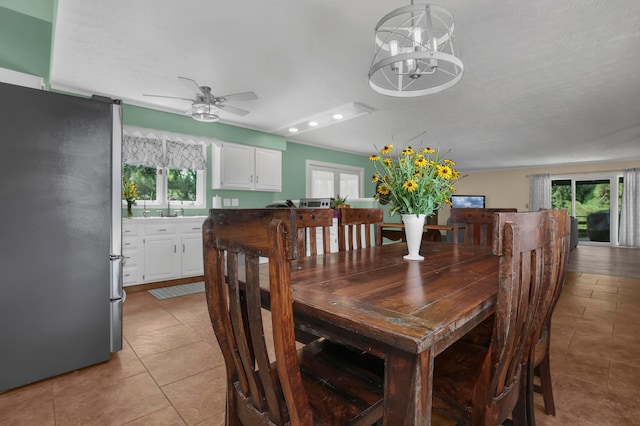 tiled dining space featuring ceiling fan with notable chandelier, sink, and a wealth of natural light