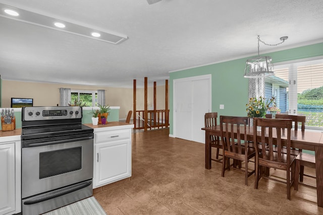 kitchen featuring stainless steel electric stove, decorative light fixtures, white cabinetry, and a textured ceiling