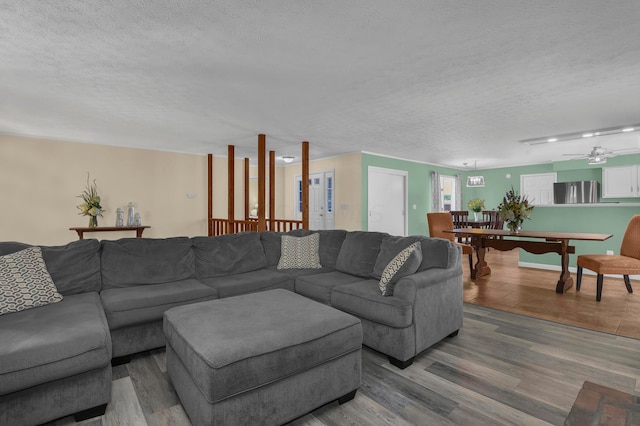 living room with ceiling fan, wood-type flooring, and a textured ceiling