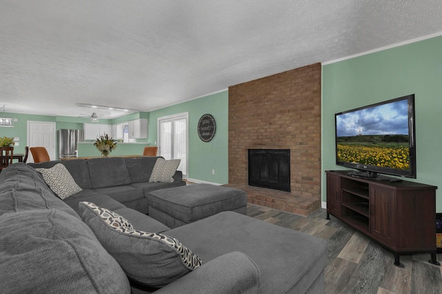 living room featuring a textured ceiling, ceiling fan, crown molding, a fireplace, and hardwood / wood-style floors