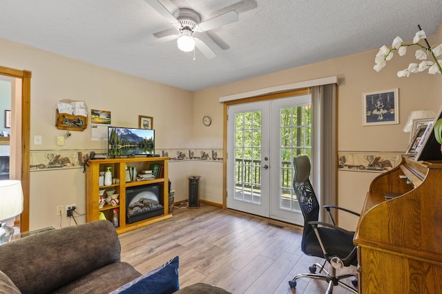 office area with french doors, light wood-type flooring, a textured ceiling, and ceiling fan