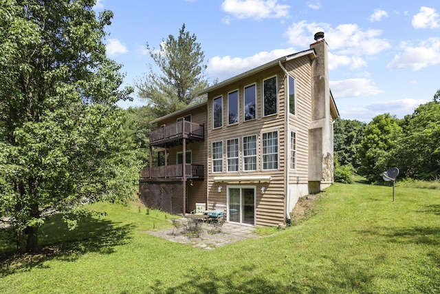 rear view of property with a yard, a balcony, and a patio