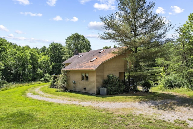 view of side of home with central air condition unit and a yard