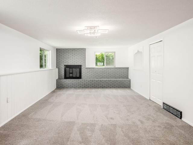 unfurnished living room featuring a textured ceiling, a fireplace, and light carpet