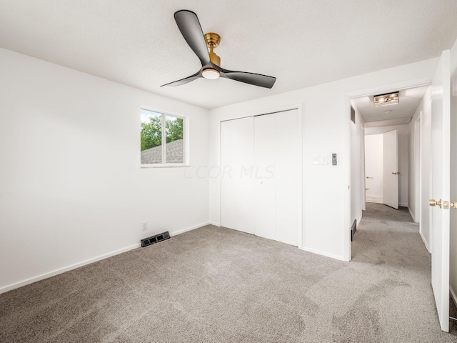 unfurnished bedroom featuring ceiling fan, a closet, and light colored carpet