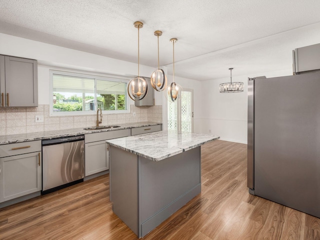 kitchen featuring a center island, sink, stainless steel appliances, backsplash, and hardwood / wood-style floors