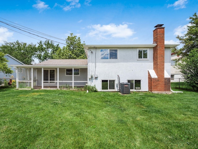 rear view of property with central AC, a sunroom, and a yard