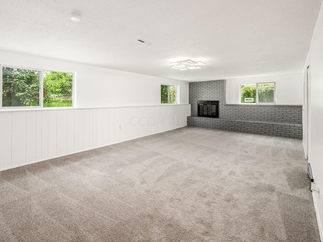 interior space featuring a fireplace, a textured ceiling, light colored carpet, and brick wall