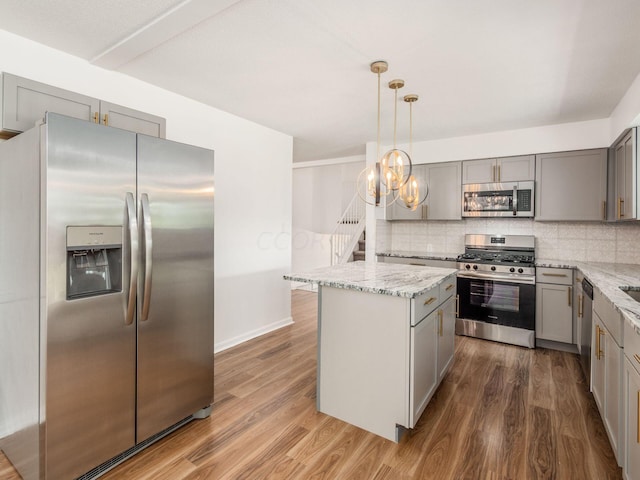 kitchen featuring dark hardwood / wood-style flooring, a kitchen island, hanging light fixtures, and appliances with stainless steel finishes