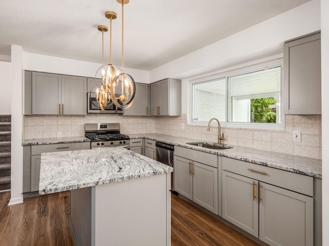 kitchen with gray cabinets, a kitchen island, sink, and appliances with stainless steel finishes