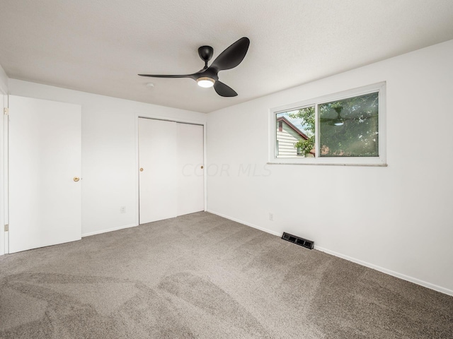 unfurnished bedroom with ceiling fan, a closet, and carpet