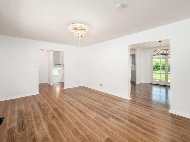 unfurnished room with dark hardwood / wood-style flooring, a textured ceiling, and a chandelier