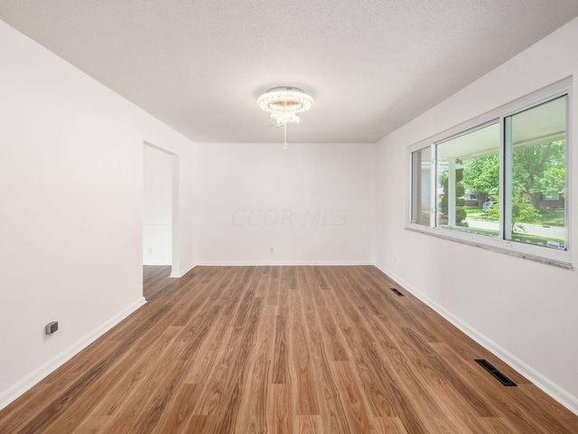 empty room with wood-type flooring and a textured ceiling