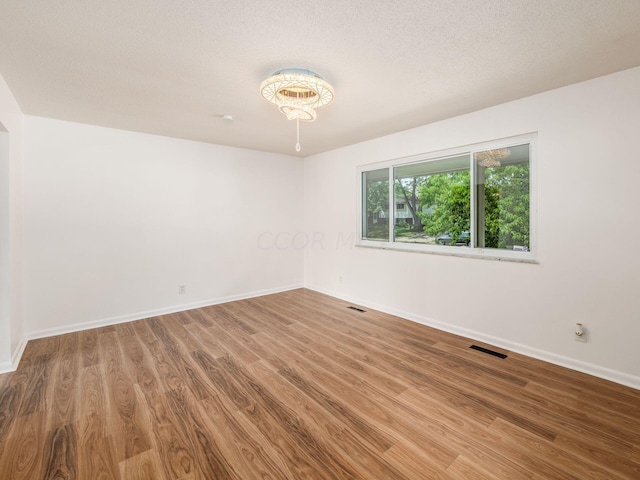 unfurnished room featuring wood-type flooring and a textured ceiling