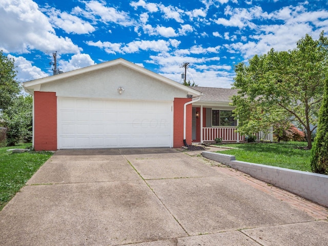 single story home with covered porch, a garage, and a front yard