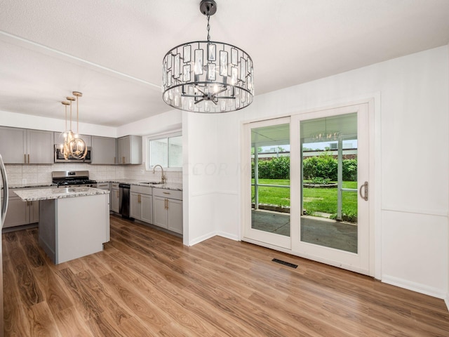 kitchen featuring stainless steel appliances, a kitchen island, hanging light fixtures, and a healthy amount of sunlight