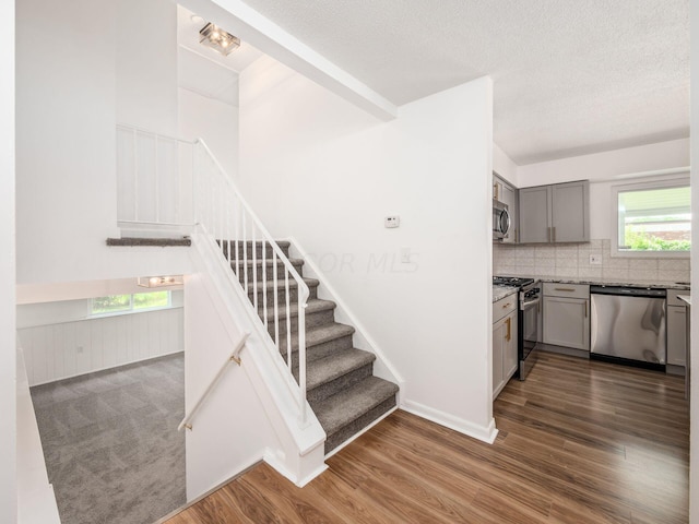 staircase with a textured ceiling and hardwood / wood-style flooring