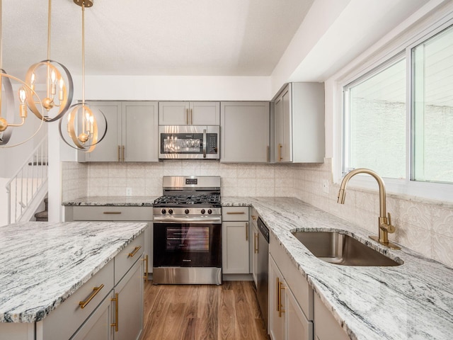 kitchen with appliances with stainless steel finishes, dark hardwood / wood-style flooring, tasteful backsplash, sink, and pendant lighting