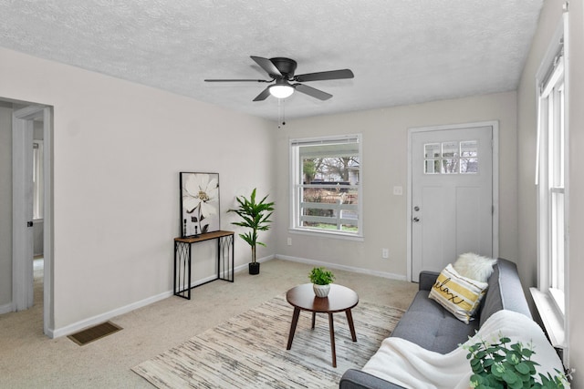 carpeted living room with ceiling fan and a textured ceiling