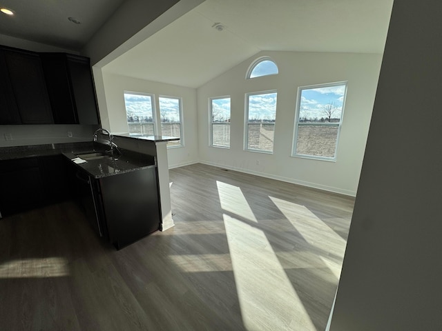 kitchen featuring dark stone countertops, sink, lofted ceiling, and light hardwood / wood-style flooring