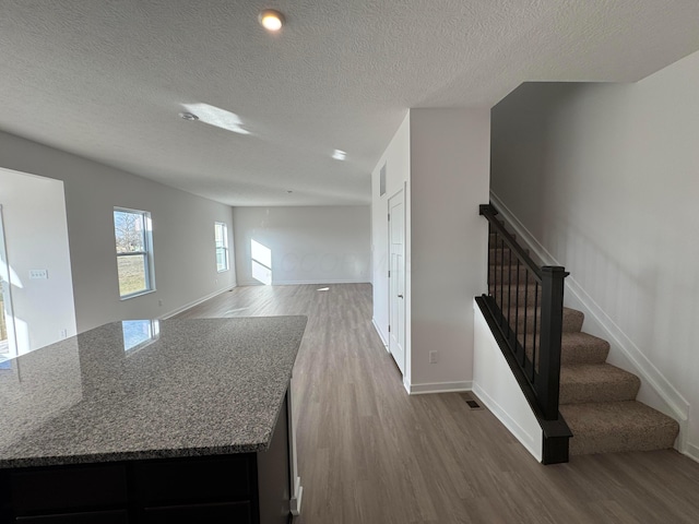 kitchen featuring wood-type flooring, light stone countertops, and a textured ceiling