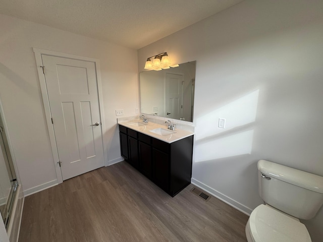 bathroom featuring a textured ceiling, vanity, hardwood / wood-style flooring, and toilet