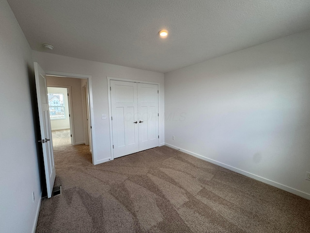 unfurnished bedroom with carpet flooring, a closet, and a textured ceiling