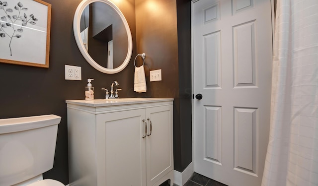 bathroom with toilet, vanity, and tile patterned floors